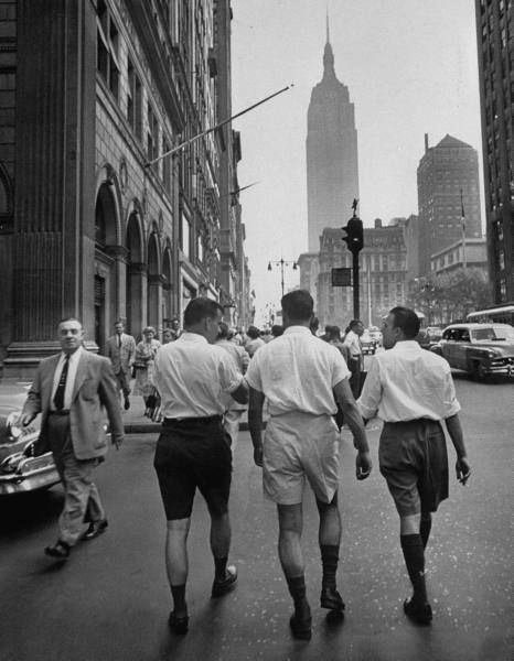 1953. "Rear view of three young businessmen wearing Bermuda shorts as they walk along Fifth Ave. during lunchtime."